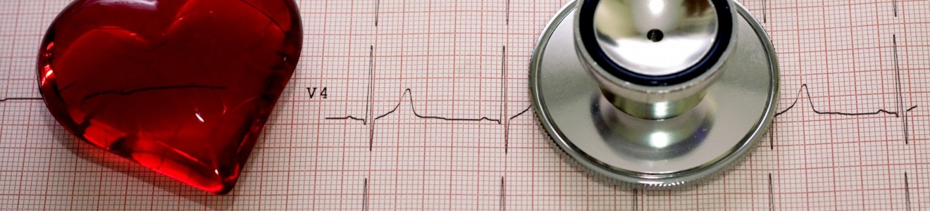 A stethoscope and a red heart-shaped object placed on an electrocardiogram (ECG) printout.