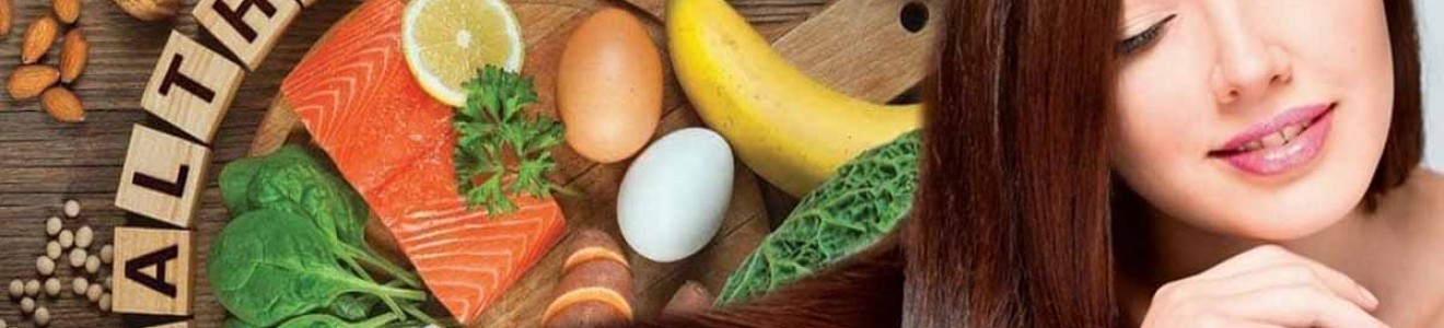 A woman with long, healthy hair resting beside a variety of nutritious foods and wooden blocks spelling 