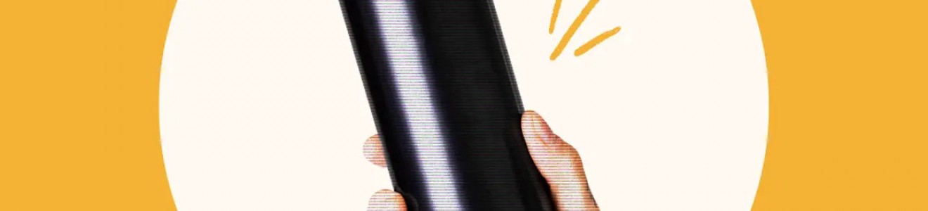 A tattooed hand holding a plain black beverage can against a circular white and orange background.