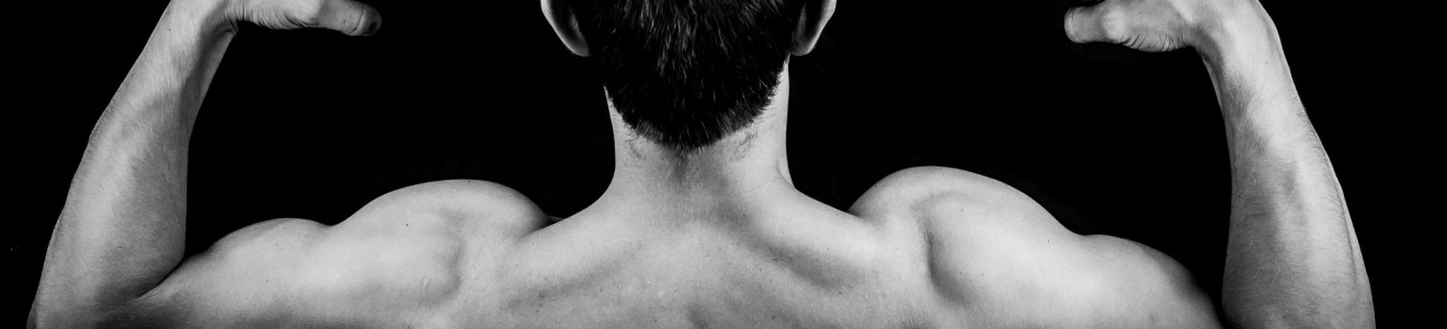 A black and white photo of a shirtless person seen from behind flexing their arm muscles against a black background.